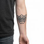 Tatuaggio semi-permanente INKON Maschera Oni applicato su un uomo – design 4 x 4 in (9x9cm), aspetto realistico dell'inchiostro, dura 10 giorni