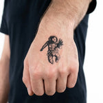 Tatuaggio semi-permanente INKON Floating Astronaut applicato su un uomo – design 2 x 2 in (5x5cm), aspetto realistico dell'inchiostro, dura 10 giorni