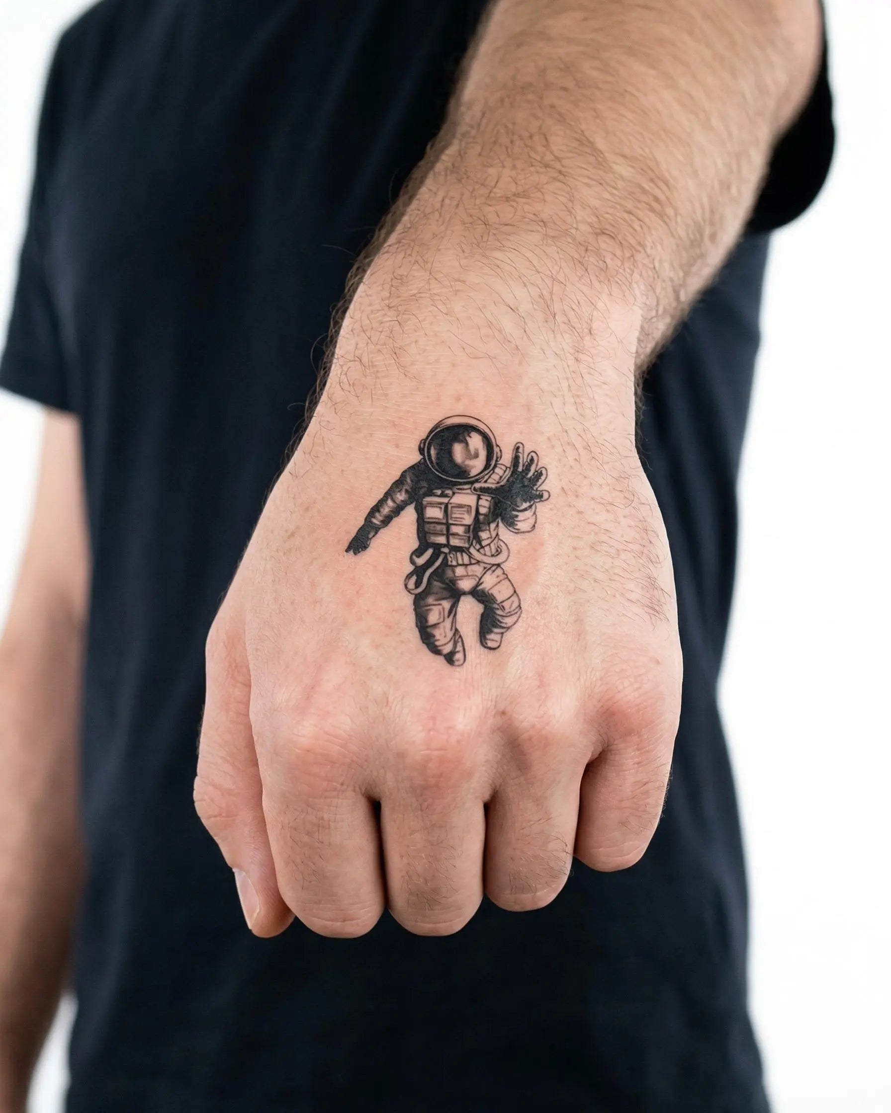 Tatuaggio semi-permanente INKON Floating Astronaut applicato su un uomo – design 2 x 2 in (5x5cm), aspetto realistico dell'inchiostro, dura 10 giorni