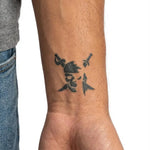Tatuaggio semi-permanente INKON Pirate Skull & Swords applicato su un uomo – design 2 x 2 in (5x5cm), aspetto realistico dell'inchiostro, dura 10 giorni