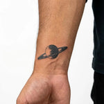 Tatuaggio semi-permanente INKON Saturn Planet applicato su un uomo – design 2 x 2 in (5x5cm), aspetto realistico dell'inchiostro, dura 10 giorni