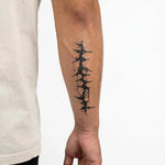 Tatuaggio semi-permanente INKON Cicatrice di Filo Spinato applicato su un uomo – design 4 x 7 in (10x17cm), aspetto realistico dell'inchiostro, dura 10 giorni